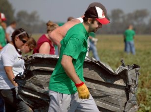 Rylan Kaip helps carry a large piece of twisted metal out of a potato field.
