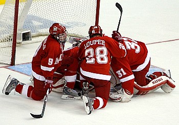 Dejected Miami players Tommy Wingels, Bill Loupee and Connor Knapp console goalie Cody Reichard (photo: Jim Rosvold).