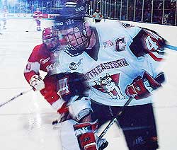 Husky Captain Jim Fahey picks up the puck behind his goal line, as Terrier Brian Collins closes in on him. (photos by Scott Weighart)