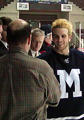 Goalie Marc Scheuer accepts his victory watch from Vince Eruzione.