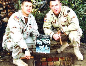 Brody Howatt (r.) and John [nl]Williams, also a former Army icer, pose over Saddam's spider hole with the Black Knights' media guide. (Courtesy Army Sports Information)