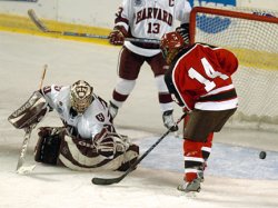 Chelsea Grills (14) sends the puck through the Harvard crease.