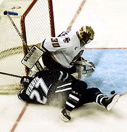 UNH's Daniel Winnik (27) and the puck crash into Boston College goaltender Matti Kaltiainen during the third period.