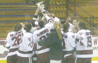 Harvard players celebrate with the ECACHL trophy.