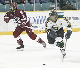 Golden Knight Nick Dodge carries the puck alongide Crimson skater Mike Taylor (photos: Lowell K. Chow).