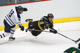 St. Norbert captain Connor Hughes dives for a loose puck past Middlebury's Eric LaFreniere.