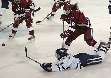 UNH's Martine Garland (2) gets a shot off from ice level as she's tripped up by Harvard's Laura Brady in the third period. (Photo: Josh Gibney)