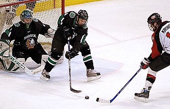 UND's Taylor Chorney plays the puck between netminder Philippe Lamoureux and SCSU's Dan Kronick (photo: John Dahl, SiouxSports.com).