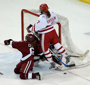 Cahow (front) takes a hit from Wisconsin's Meghan Duggan during action in the 2007 NCAA tournament (photo: John E. Van Barriger, words-photos.com).