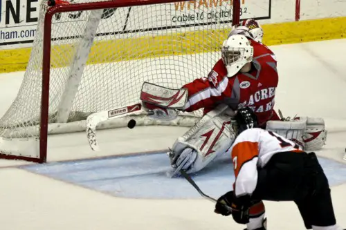 RIT's Sean Murphy (bottom) sends the puck past Sacred Heart goaltender Steven Legatto in the second period (photo: Nick Serrata).