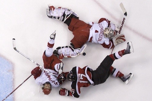 Wisconsin goaltender Scott Gudmandson dives out to cover the puck in a pileup in front of his crease (photo: Jim Rosvold).