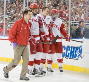 Wisconsin's Derek Stepan is helped off the ice by Andy Hrodey, Blake Geoffrion and Podge Turnbull after crashing into the boards (photo: Melissa Wade).