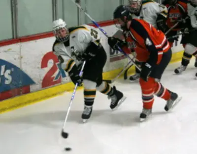 St. Norbert's Brandon Longley and Salem State's Brett Noll battle for a loose puck (photo: Matthew Webb).