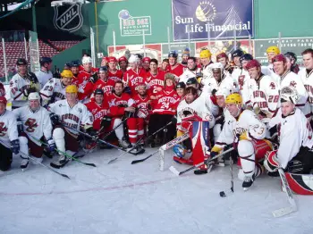 Old rivalries took a back seat to good times at Fenway Park when alumni from Boston University and Boston College skated. Afterward, the teams pose for photos with Travis Roy (photo: Brian Sullivan).