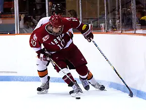 Eric Kroshus (Harvard - 10) plays the puck along the boards away from Derrick Pallis (Princeton - 5). (Shelley M. Szwast)