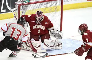 Denver's Paul Phillips is able to poke the puck away from UNO's Zahn Raubenheimer as goalie Sam Brittain defends the goal. Denver beat Nebraska-Omaha 4-2 Saturday night at Qwest Center Omaha. (Photo by Michelle Bishop) (Michelle Bishop)