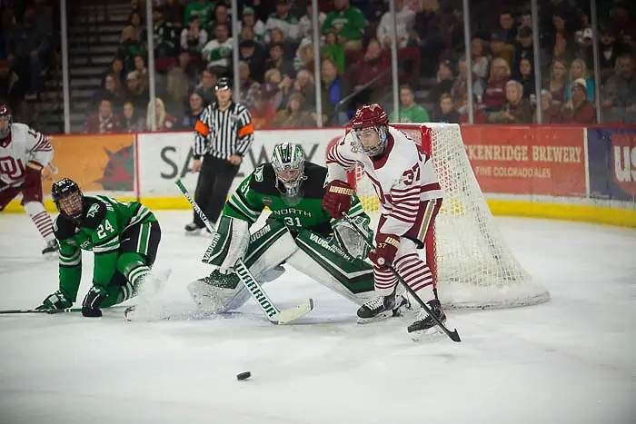 Adam Scheel of North Dakota looks at the puck while Denver's Hank Crone sizes up a rebound, North Dakota vs. Denver at Magness Arena, Nov. 15, 2019. (Candace Horgan)