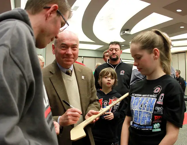 Mike Kemp, former Omaha hockey coach and current Associate Athletic Director, signs an autograph for Michael Burns (left) during the Frozen Four send-off ceremony Monday night in Omaha. (Photo by Michelle Bishop) (Michelle Bishop)